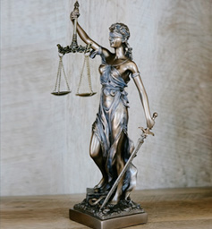 Statue of lady liberty with sword in left hand and balanced scale in the right hand.